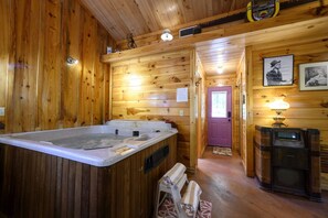 A wooden cabin interior with a hot tub, a door, and a vintage radio.