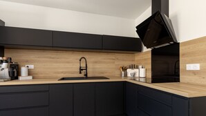 Une cuisine moderne dotée d’un plan de travail en bois, de meubles noirs, d’un évier encastré et d’une machine à café.