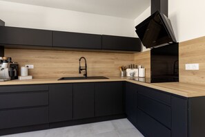 A modern kitchen with a wooden countertop, black cabinets, a built-in sink, and a coffee machine. - SmartStay P.Cézanne - Proche L'Isle-sur-la-Sorgue (Lagnes)