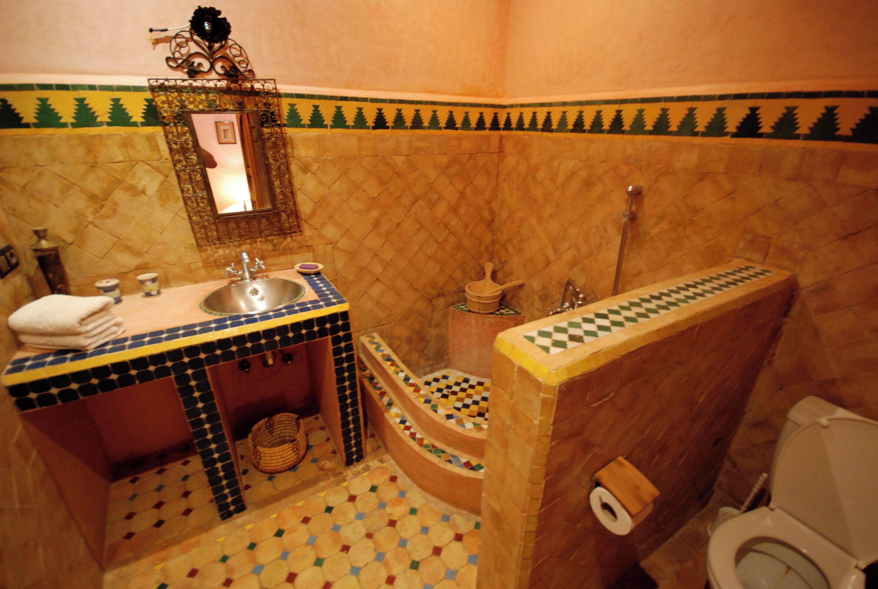 Un baño con lavamanos, espejo, inodoro y zona de ducha.