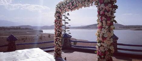 A wedding arch decorated with flowers overlooking a body of water.