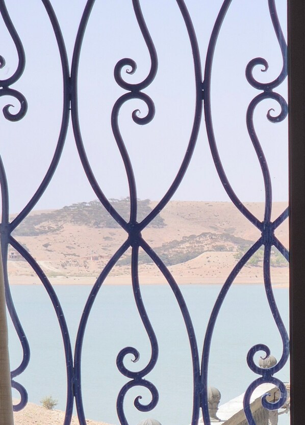 A view through a metal gate with a landscape in the background. - RIVE DU LAC (Lalla Takarkoust)