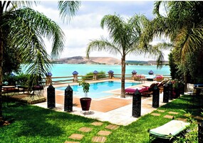 A poolside area with lounge chairs, a small pool, and a view of the sea.