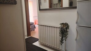 Un couloir avec un radiateur, un miroir et un réfrigérateur.