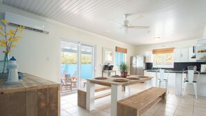 A spacious kitchen with a dining area, featuring a large table, benches, and a ceiling fan.