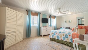 A bedroom with a bed, dresser, TV, and a ceiling fan.