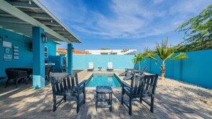 An outdoor pool area with a blue wall, lounge chairs, and a small table.