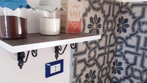 A kitchen with a gas stove, a shelf with kitchen items, and patterned tiles. - The house of the islands Sea View ( The House Of The Islands ) (Marausa Lido)