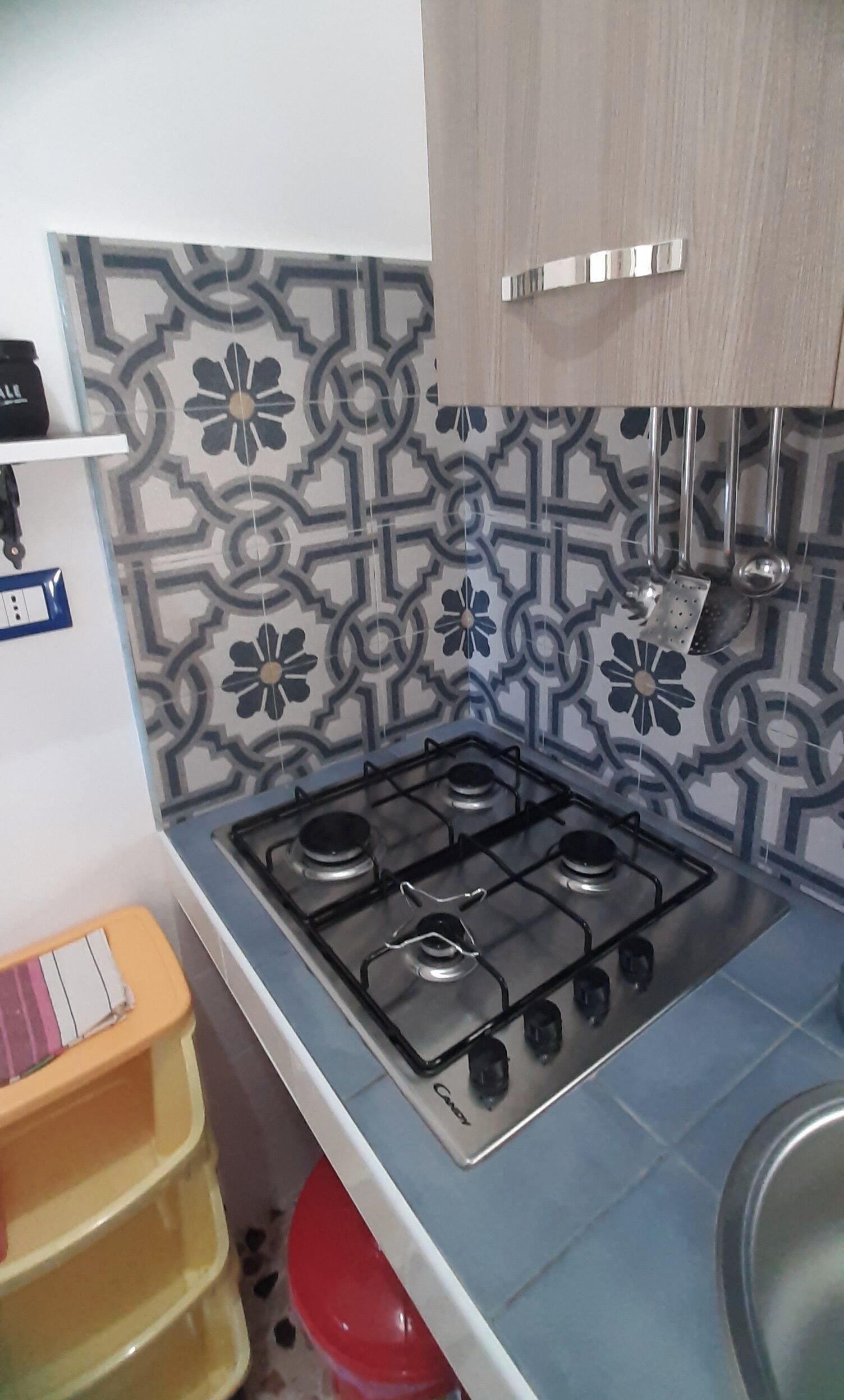 Une cuisine équipée d’une cuisinière à gaz, d’un plan de travail décoré et d’un évier.