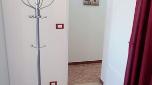 A hallway with a coat rack, a red curtain, and a painting of red flowers on the wall. - The house of the islands Sea View ( The House Of The Islands ) (Marausa Lido)