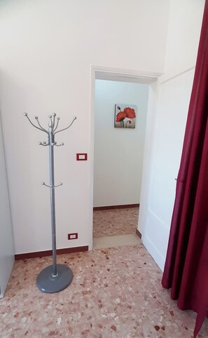 A hallway with a coat rack, a red curtain, and a painting of red flowers on the wall. - The house of the islands Sea View ( The House Of The Islands ) (Marausa Lido)