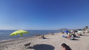 A beach with people sunbathing and swimming, umbrellas, and a clear sky. - The House of the Islands: Ocean View (The House of the Islands) (Marausa Lido)
