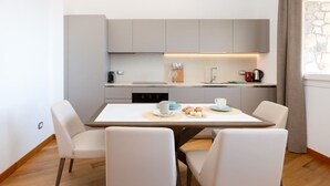 A modern kitchen with a dining table, chairs, and a coffee machine.
