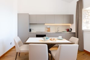 A modern kitchen with a dining table, chairs, and a coffee machine.