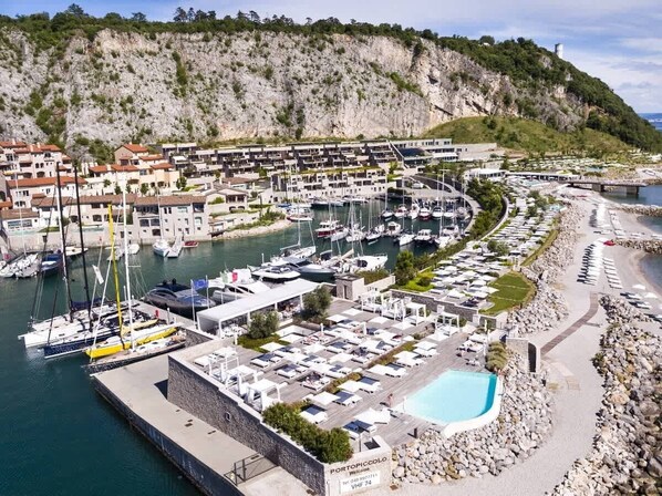 A marina with boats, a swimming pool, and a coastal town.