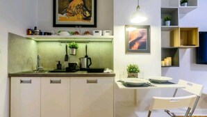 Une cuisine moderne avec un coin repas, comprenant un îlot central, des meubles de cuisine blancs et un luminaire suspendu.