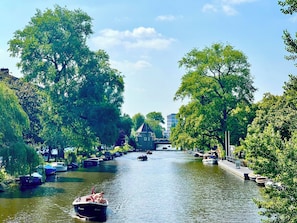 A canal lined with boats and trees, with a bridge in the background. - A peaceful haven in the bustling city of Amsterdam (Amsterdam)
