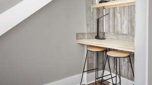 A corner workspace with a desk, two stools, and a shelf unit against a wooden wall. - Charming 4-bedroom 3bath house in terrific Florence with WiFi, AC (Florence)