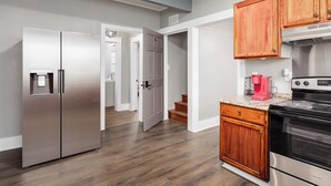 A kitchen with a stainless steel refrigerator, wooden cabinets, a black stove, and a countertop with a coffee maker. - Charming 4-bedroom 3bath house in terrific Florence with WiFi, AC (Florence)