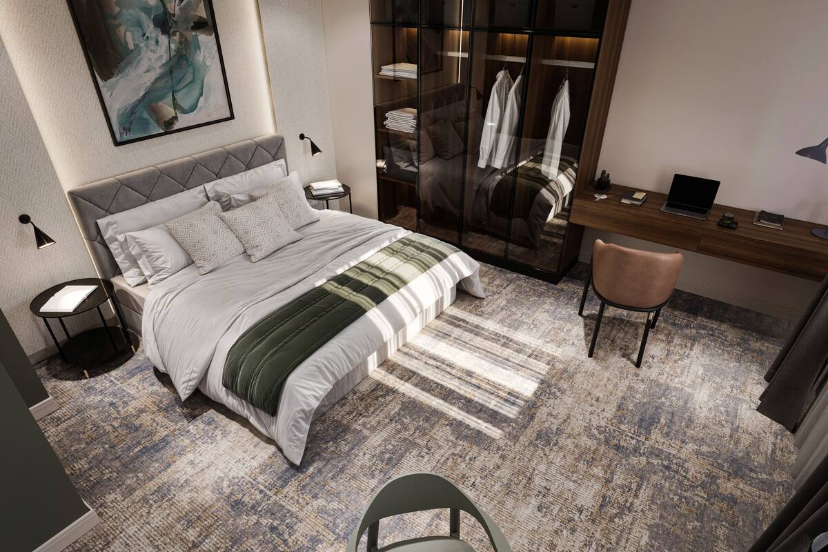 Ein modernes Hotelzimmer mit einem großen Bett, einem Schreibtisch, einem Stuhl und einem Kleiderschrank.