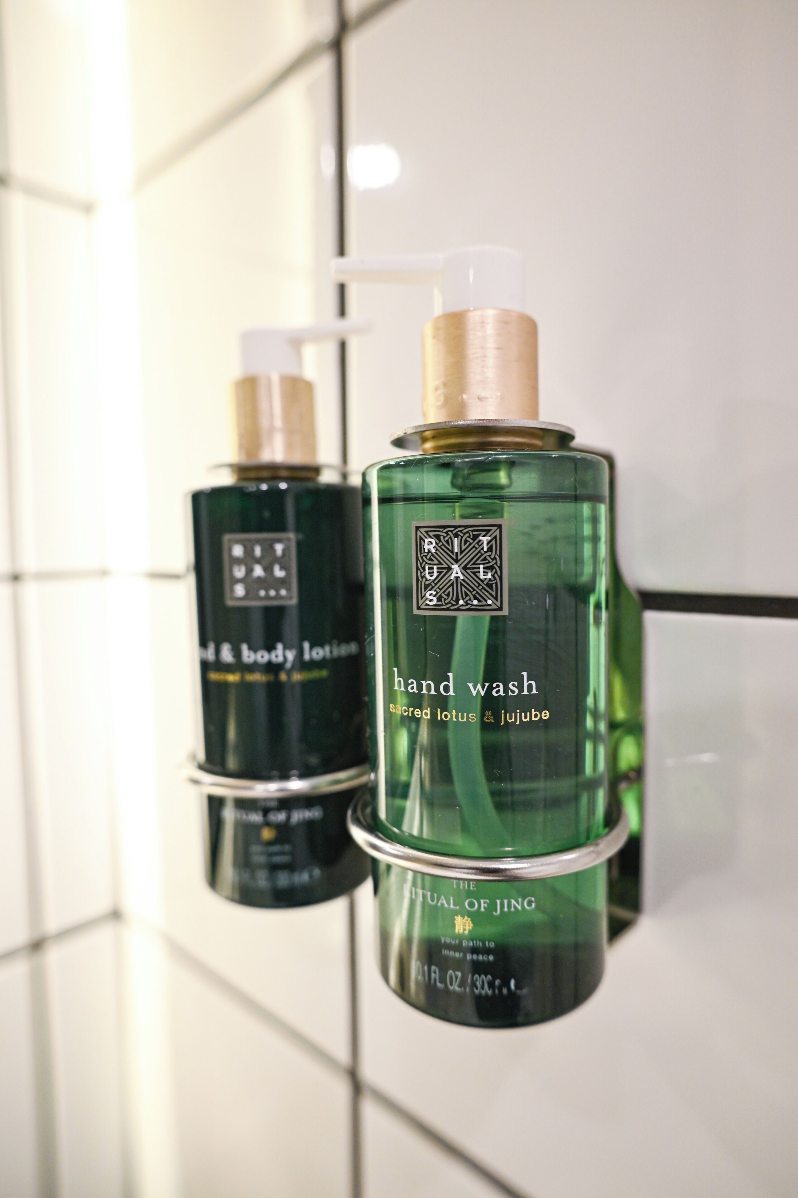Two bottles of hand wash lotion on a tiled surface.