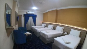 Une chambre d’hôtel avec deux lits simples, un petit bureau, une chaise et un grand miroir.