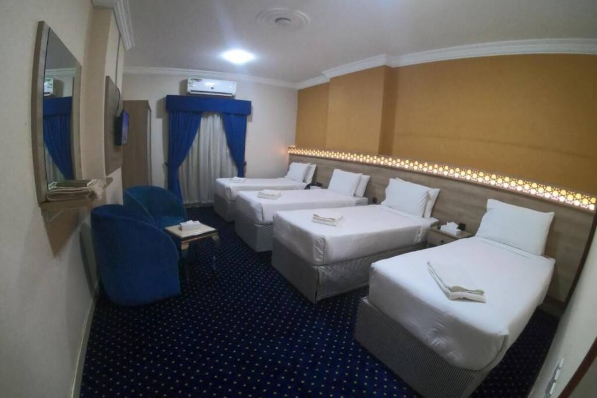 A hotel room with two single beds, a small desk, a chair, and a large mirror.