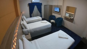 Une chambre d’hôtel avec deux lits simples, un bureau, une chaise, une télévision et un miroir.