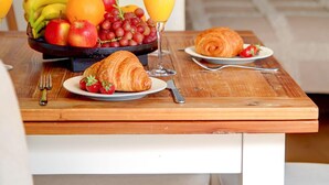 A breakfast table with fruits, juice, and croissants in a hotel room.