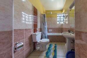 Un baño con inodoro, lavamanos, bañera y cortina de ducha.