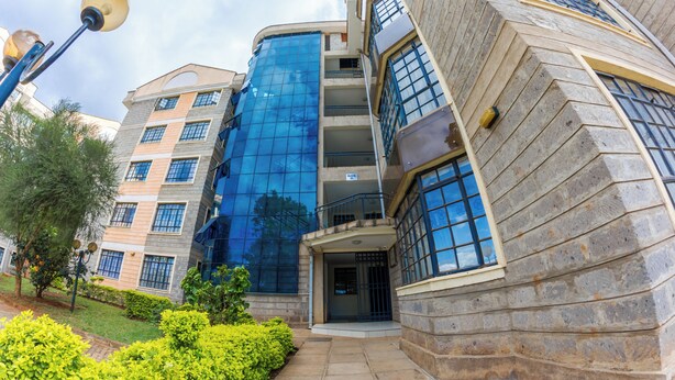 A multi-story building with a modern architectural design, featuring large windows and a stone facade. - Takdiri Home Superior (Nairobi)
