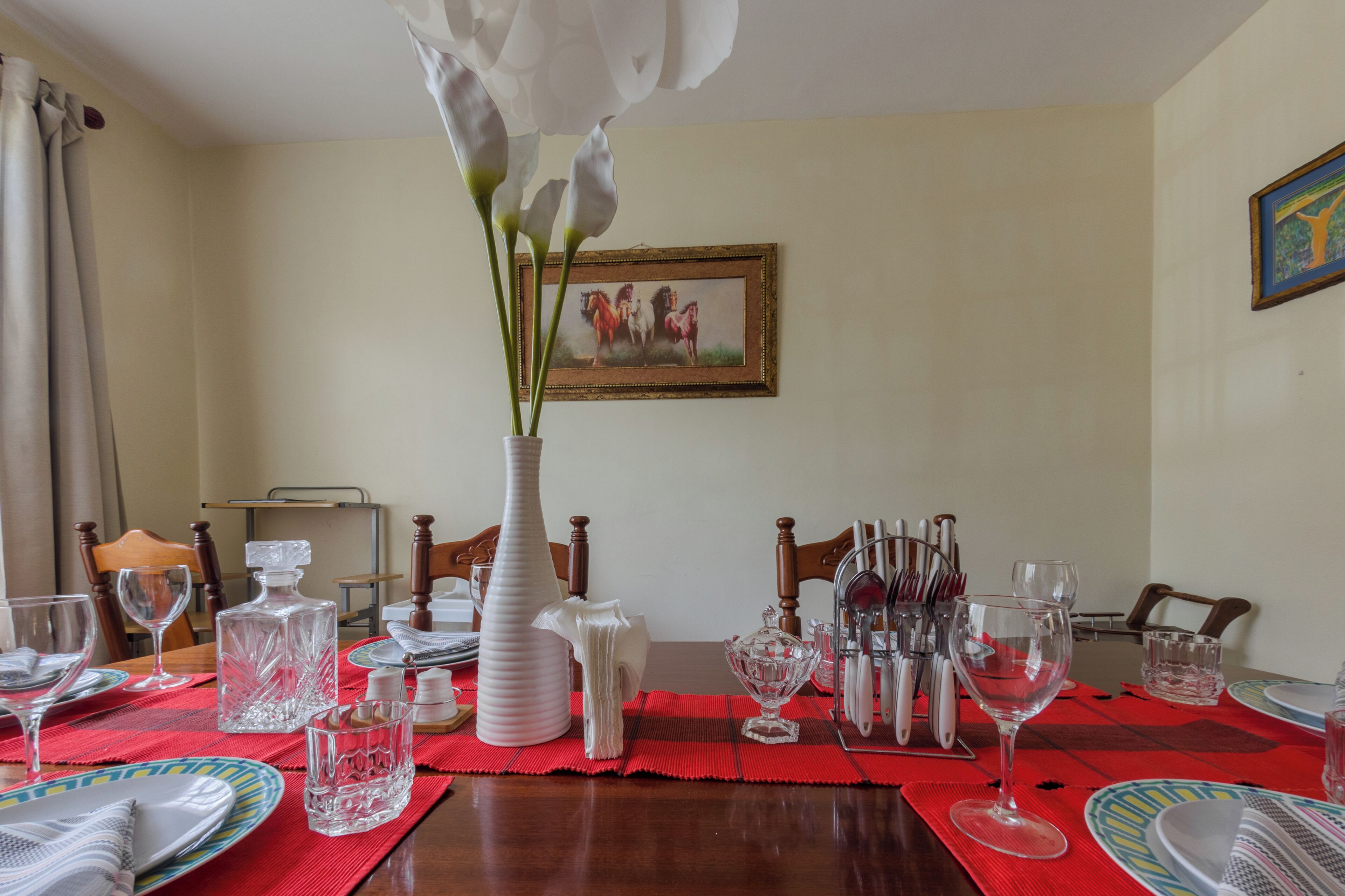 Uma mesa de jantar posta com pratos, copos e um vaso de flores.