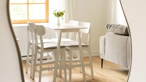 A dining area with a white table and chairs, a vase with a plant, and a window with curtains. - Maison Rasco • One-Bedroom Apartment • King Size Bed • Old Montreal • Full Kitchen • Stone Wall • Pet Friendly • Self Check-In Access • Wi-Fi • AC (Montreal)
