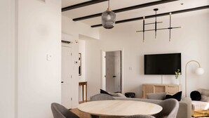 Una sala de estar moderna con una mesa redonda de madera, sillas tapizadas en gris, un televisor de pantalla plana en la pared y un diseño minimalista con vigas a la vista y una lámpara colgante.
