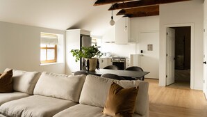 Ein modernes Wohnzimmer mit einer Couch, einem Esstisch und einer Küche im Hintergrund.