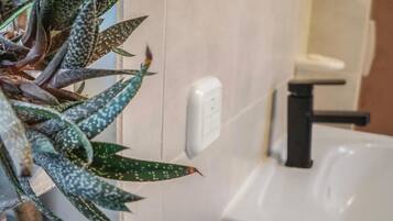 A bathroom with a white sink, a black faucet, and a wall-mounted light switch.