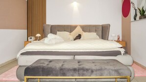 Un dormitorio moderno con una cama grande, una mesita de noche con una lámpara y un banco.