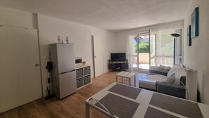 A compact living space with a kitchenette, a dining area, and a seating area with a view of the outdoors. - Renovated Apartment in Seignosse Penon - Walk to Beach & Shops, Free Parking, Wi-Fi (Seignosse)