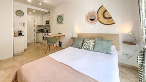 A modern bedroom with a bed, bedside table, and a view of a kitchen and living area.