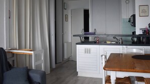 Eine kleine Küche mit einem Holztisch, weißen Schränken und einem eingebauten Backofen.