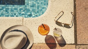 A hat, sunglasses, and two drinks on a sun lounger by a pool. - Stoke Lodge Hotel (Dartmouth)