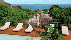 A poolside area with lounge chairs and a view of the sea. - AURA 1 - Luxury with Private Pool and View in Anse Marcel (Saint-Martin)