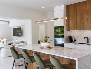A modern kitchen with a marble countertop, wooden cabinets, and a central island with bar stools.