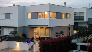 A modern two-story house with a covered patio, a staircase, and a well-lit entrance. - Three-Bedroom house with Jacuzzi & 2 Parkings (Vodice)