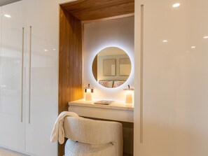 A bathroom with a vanity, a round mirror, and two wall-mounted lamps.