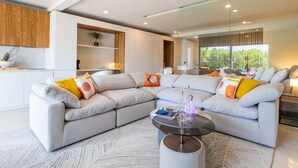 A modern living room with a sectional sofa, a glass coffee table, and a built-in shelving unit.