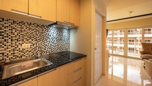 A modern kitchen with a black countertop, wooden cabinets, and a tiled backsplash.