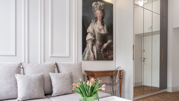 A modern living room with a white sofa, a white coffee table with a vase of flowers, and a large painting on the wall. - Native Apartments Starowiślna 43 (Kraków)