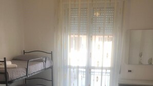 A dormitory room with bunk beds, a desk, and a window with sheer curtains. - Barone Beach Hotel (Rimini)