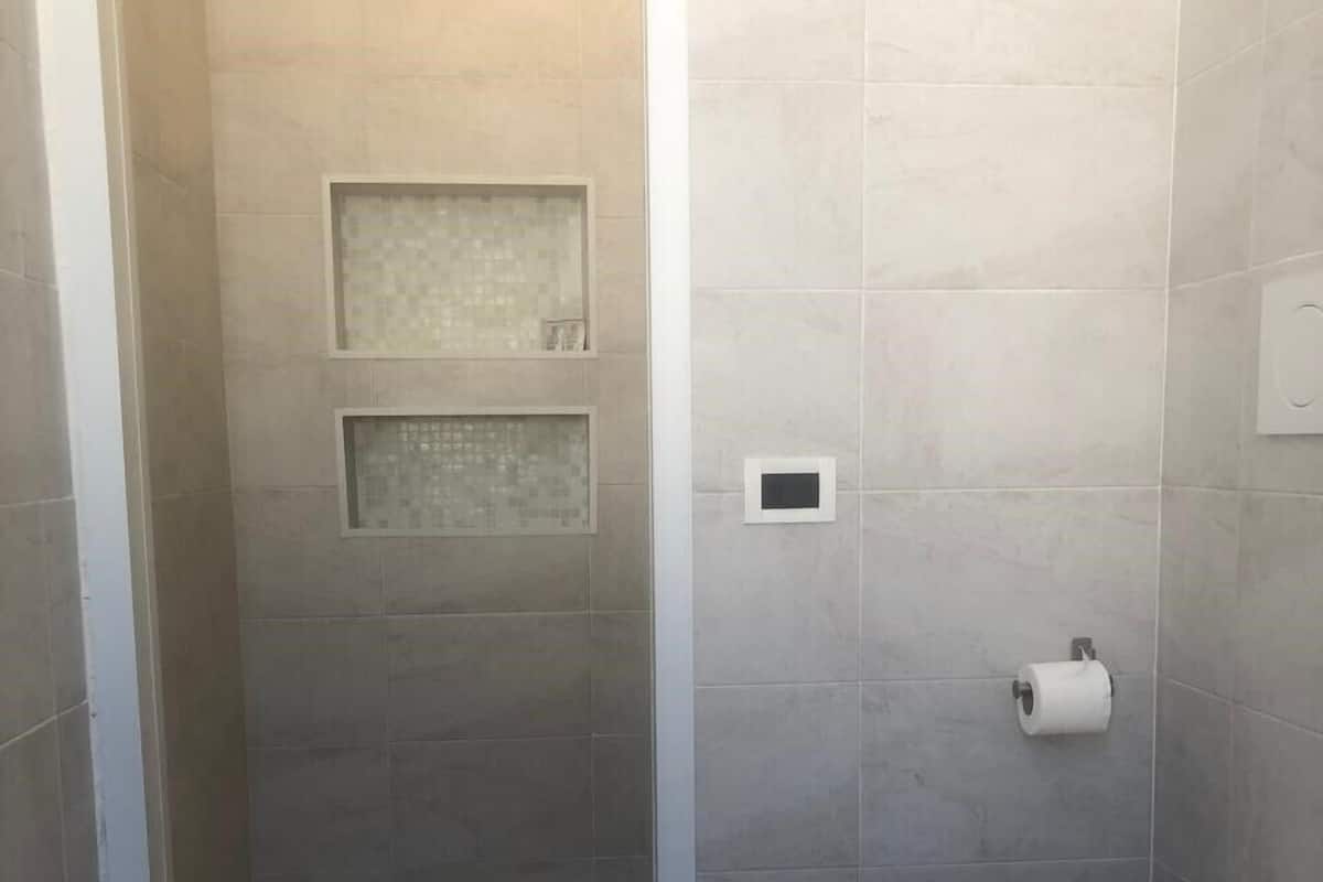 A small bathroom with a shower, toilet, and a towel rack.
